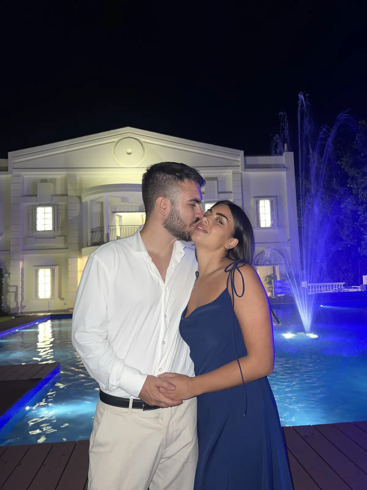 Davide e Marika abbracciati davanti a una fontana illuminata